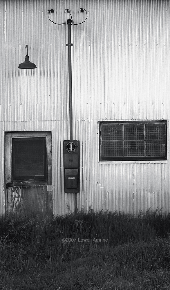Side of corrugated tin building with door, electrical box, window